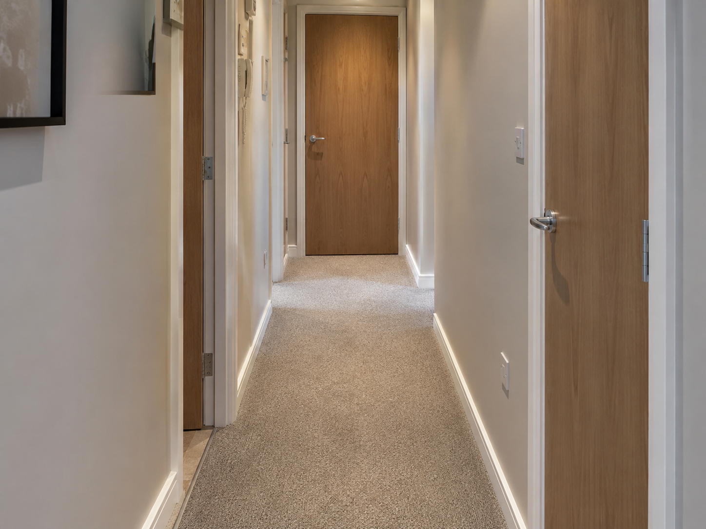 Apartment hallway with neutral carpet in a narrow space
