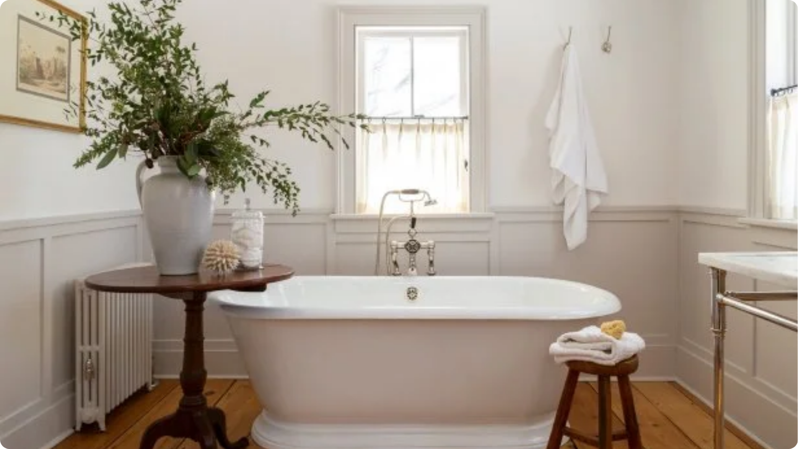 Floor-mounted bath mixer in brushed gold beside a freestanding bathtub in a modern farmhouse bathroom